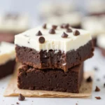 A slice of slutty brownie showing layers of cookie dough, Oreos, and brownie